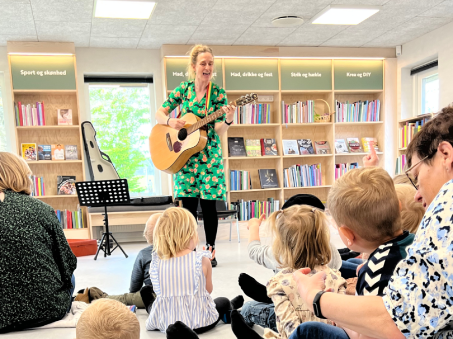 En kvinde med en guitar foran en gruppe børn.